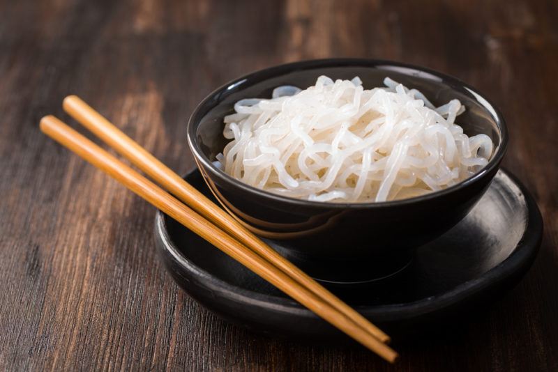 A black bowl with konjac root noodles and chopsticks