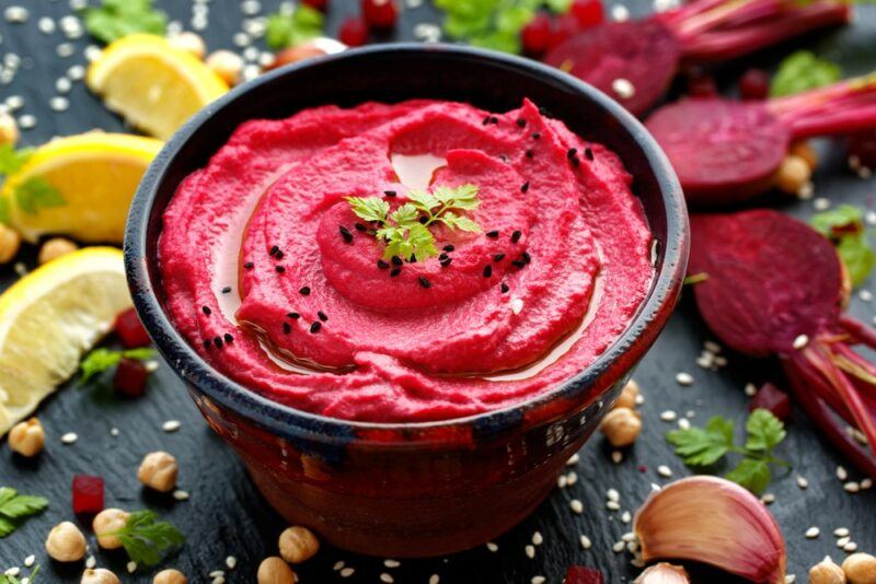 A black table with a bowl of pureed beetroot, plus a collection of fresh ingredients