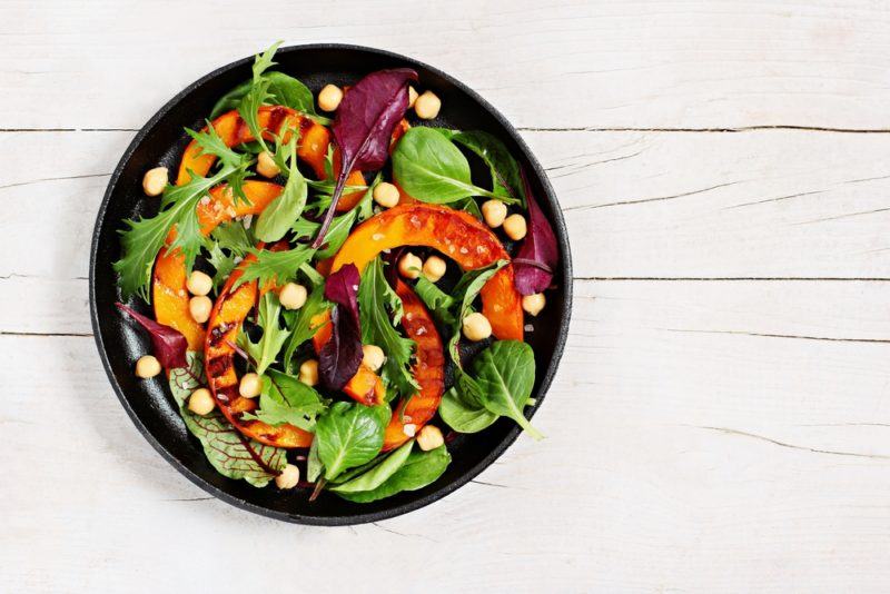 A black bowl of a vibrant salad on a white wooden table