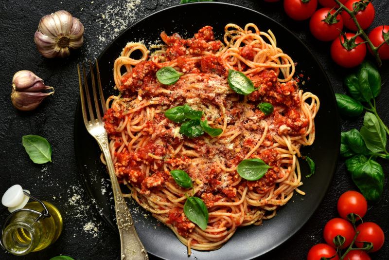 A black bowl with spaghetti and meat pasta