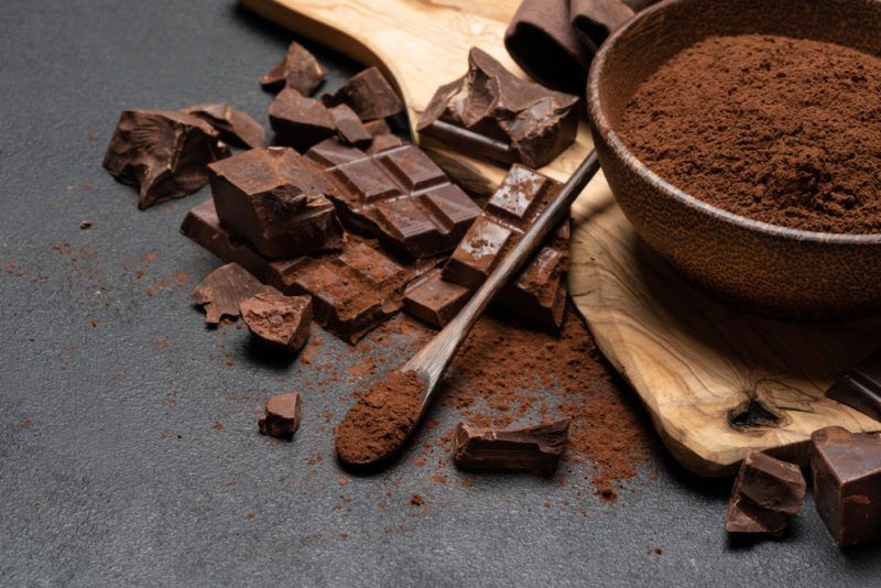 A black bowl with cocoa powder and dark chocolate