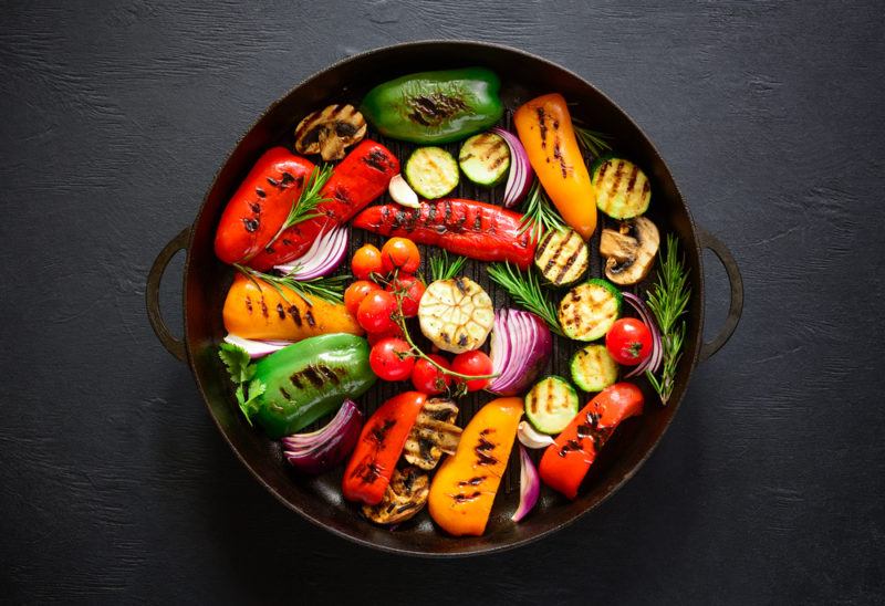 A black dish of fresh vegetables that have been grilled