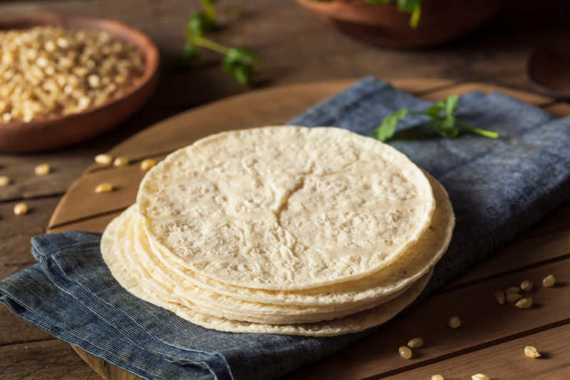 A black cloth with fresh tortillas | Food For Net A black cloth with a stack of fresh tortillas and some type of nut or grain in the background