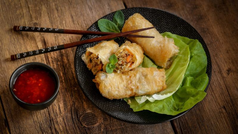 A black dish that contains fried spring rolls