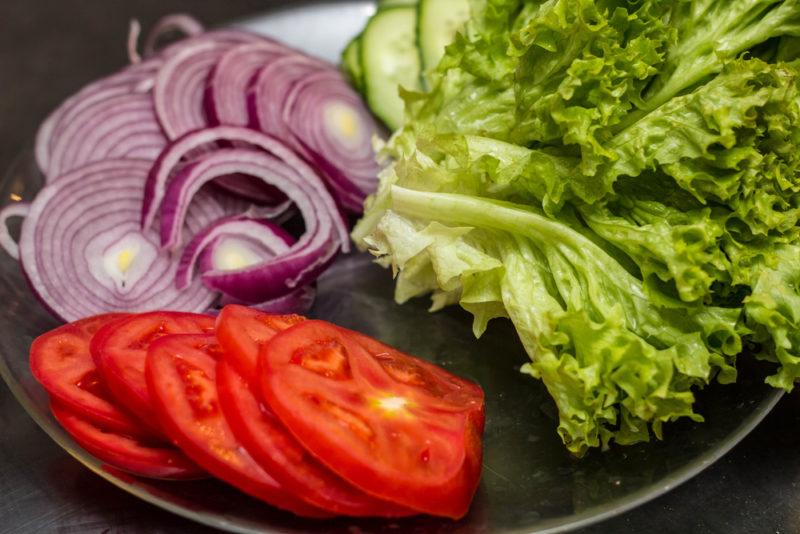 A black dish of lettuce, tomatoes and onions | Food For Net A black dish with lettuce, tomatoes, and onions
