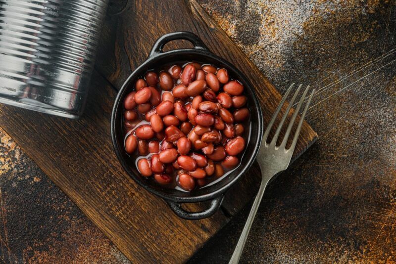 A small black dish filled with baked beans next to a fork