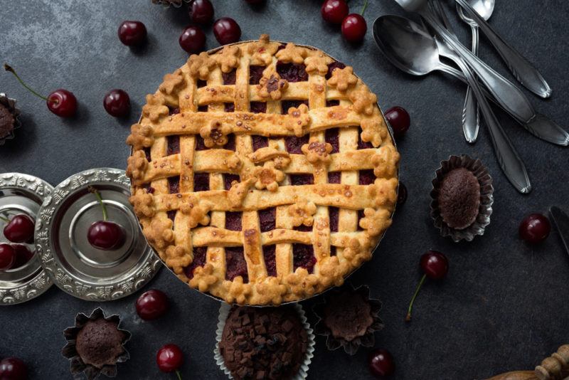 A black forest pie in a dish with cherries and chocolate cupcakes around it