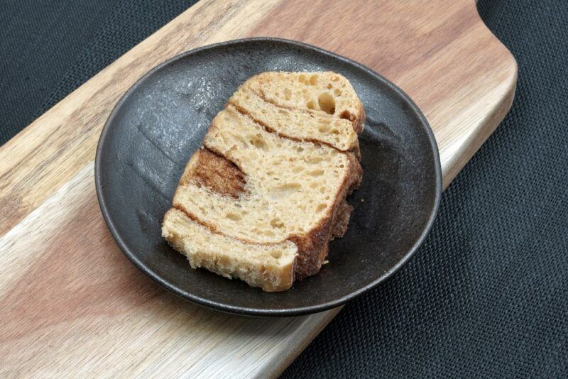 A slice of cinnamon spiced sourdough on a black plate