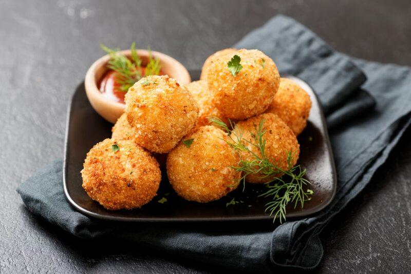 A small black plate containing croquettes and dip