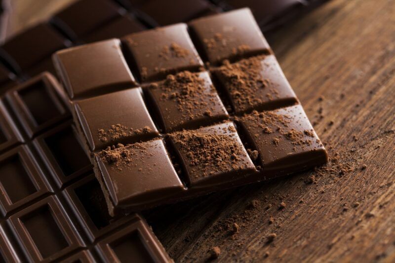 Squares of chocolate on a wooden table, including milk and dark chocolate