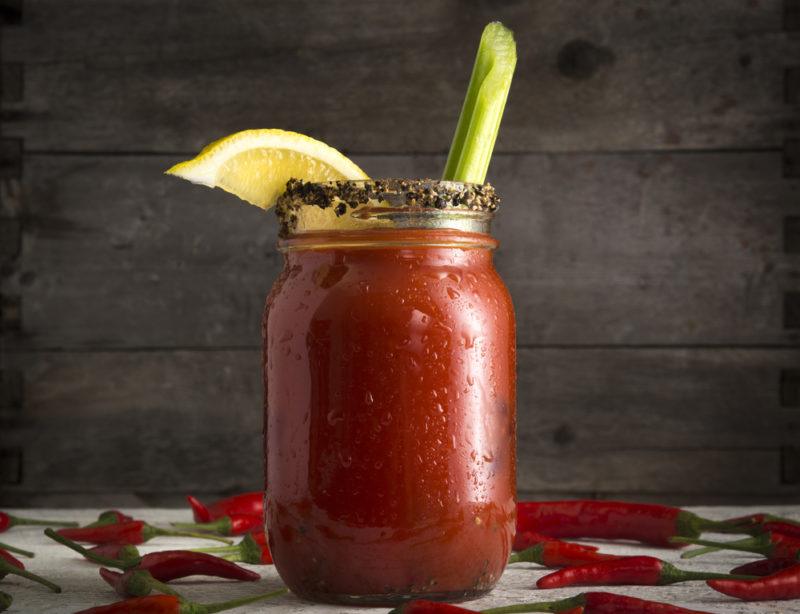 A bloody smoke tequila cocktail garnished with celery and a wedge of lemon