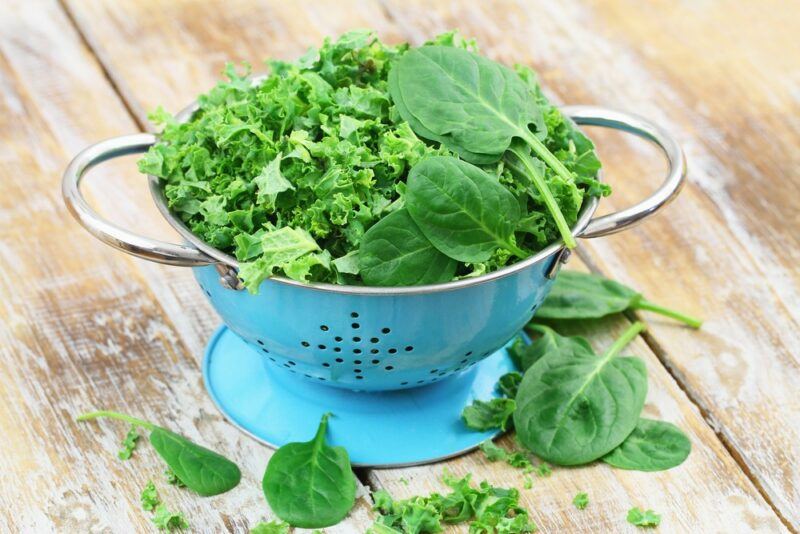 A blue and white container with spinach and kale