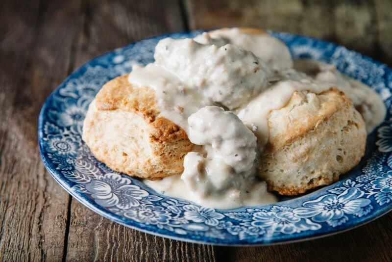 A blue and white plate with freshly baked biscuits topped with white gravy