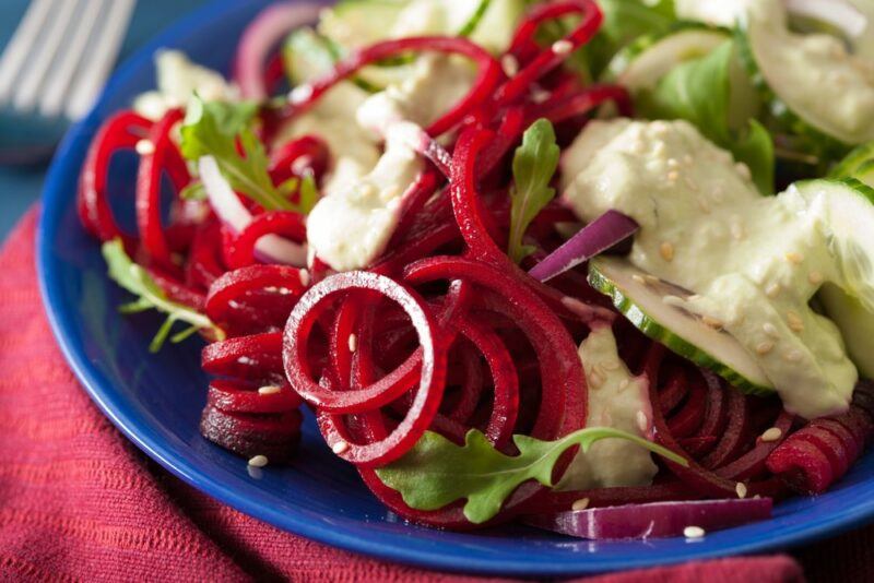 A blue plate with beet noodles, feta, and greens