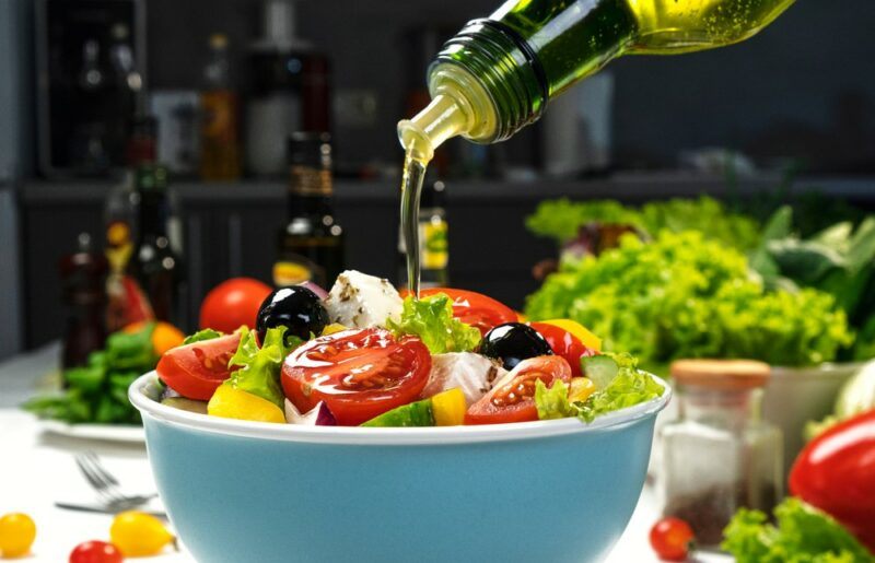 A blue bowl with a fresh salad that's been drizzled with olive oil