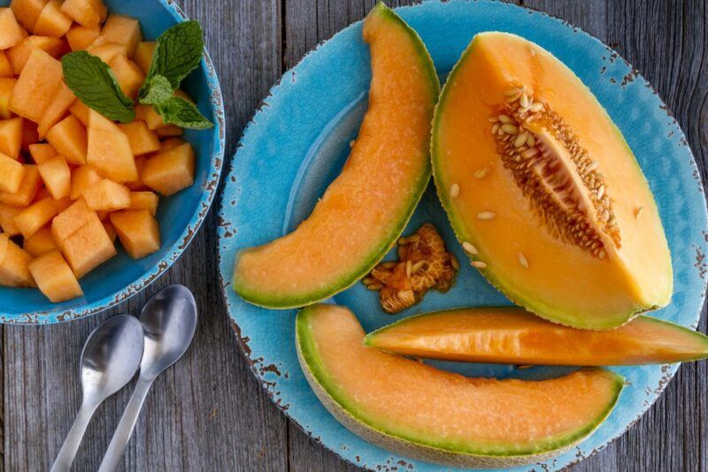 A blue platewith wedges of cantaloupe, next to a small bowl of cantaloupe chunks