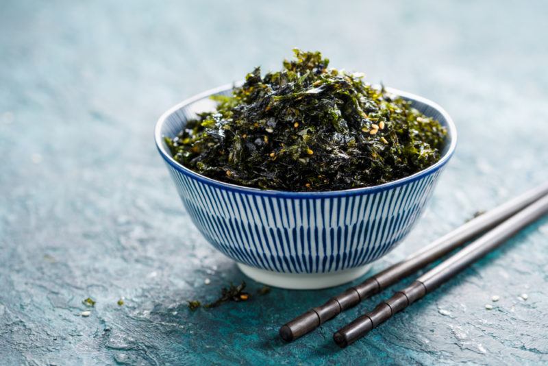 A blue and white bowl that contains cooked seaweed