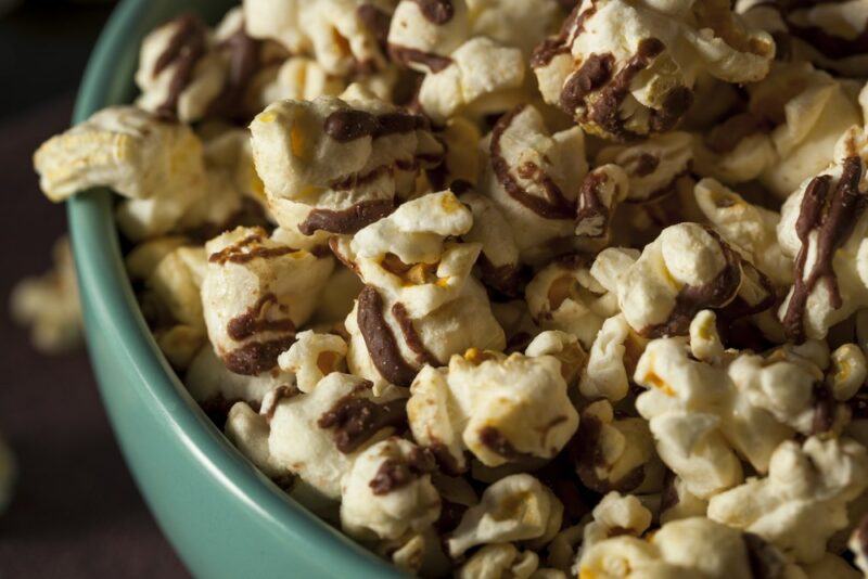 A blue bowl with caramel popcorn drizzle popcorn