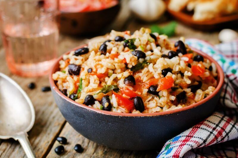 A blue bowl with a cooked rice meal that has black beans on the top