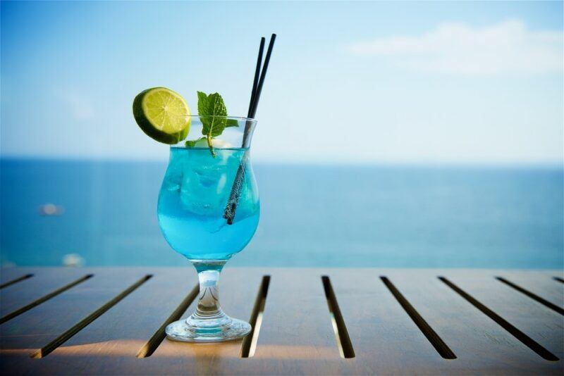 A bright blue hurricane cocktail against a light blue sea