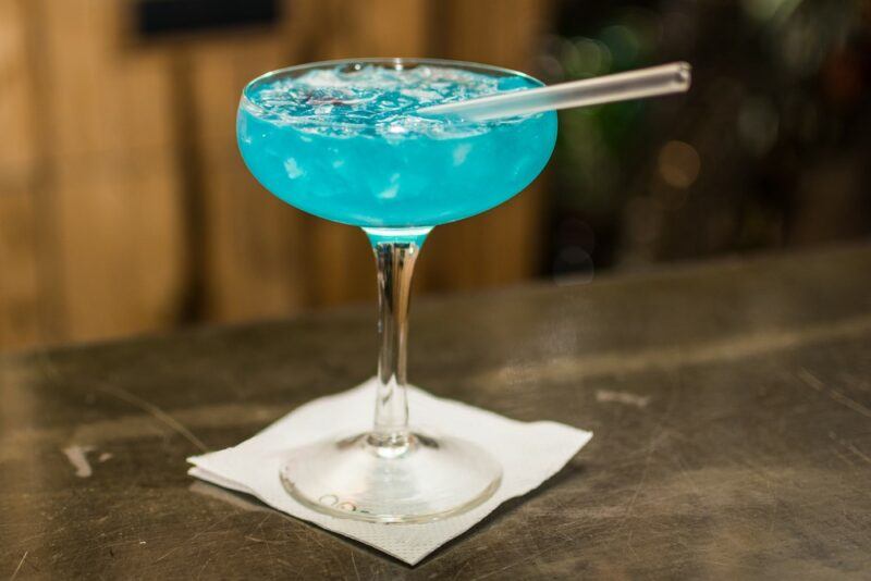 A single blue ocean breeze cocktail with a short straw