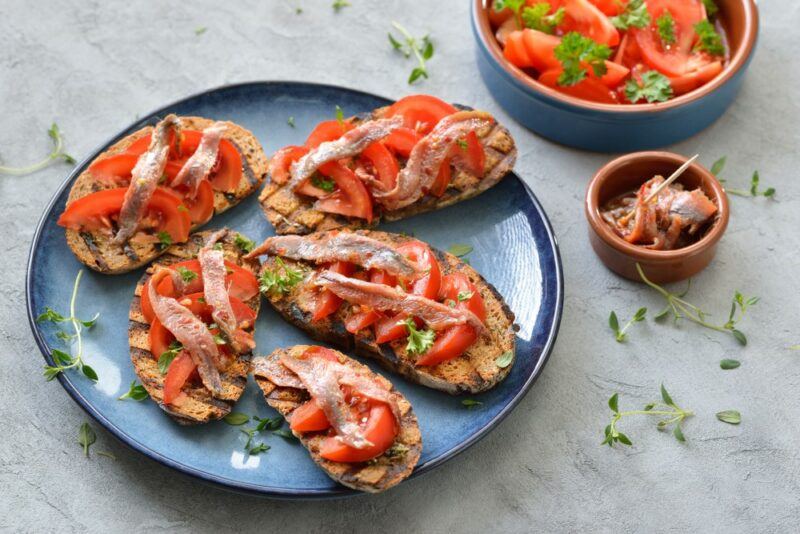 A light blue plate with appetizers that have anchovies on top