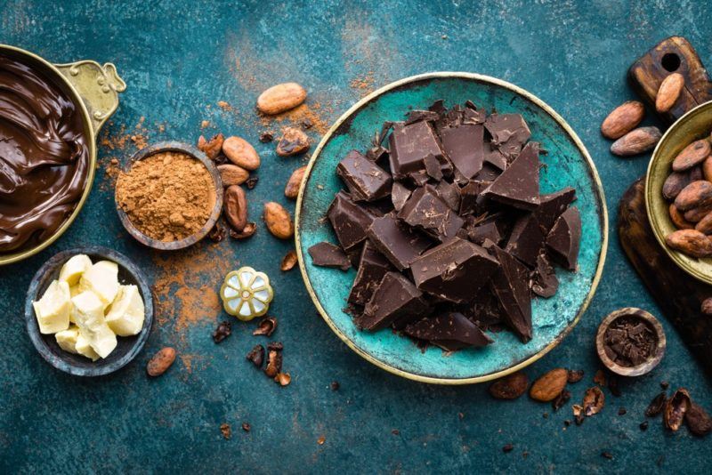 A blue plate with dark chocolate, cocoa powder, cocoa beans, and more