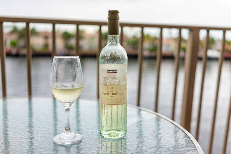 A table with a bottle and a glass of pinot gris, looking out onto the water