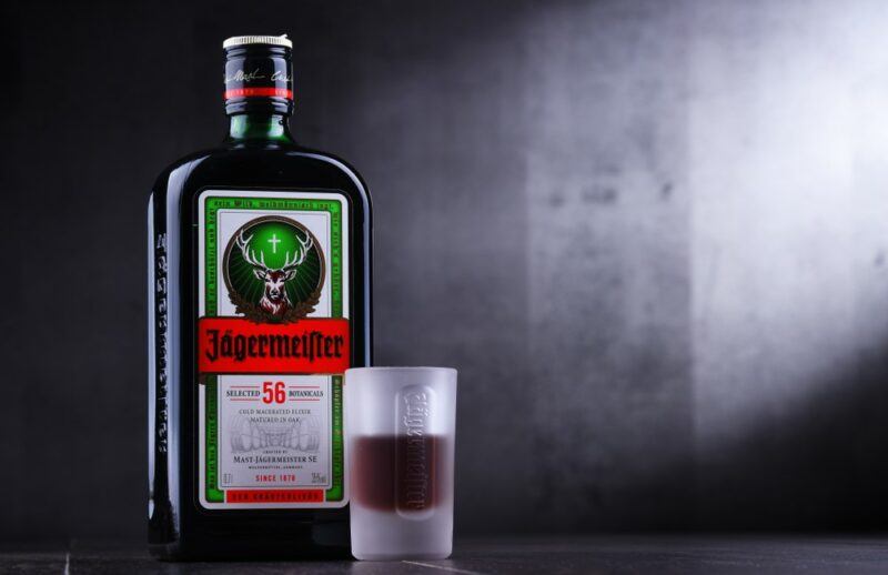 A bottle of Jägermeister on a bar, next to a shot of the liqueur