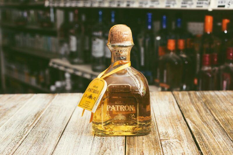 A bottle of gold tequila on a wooden table in a bar