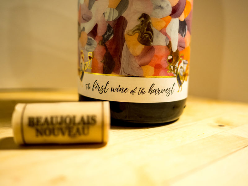 A bottle of beaujolais nouveau next to a cork from the wine