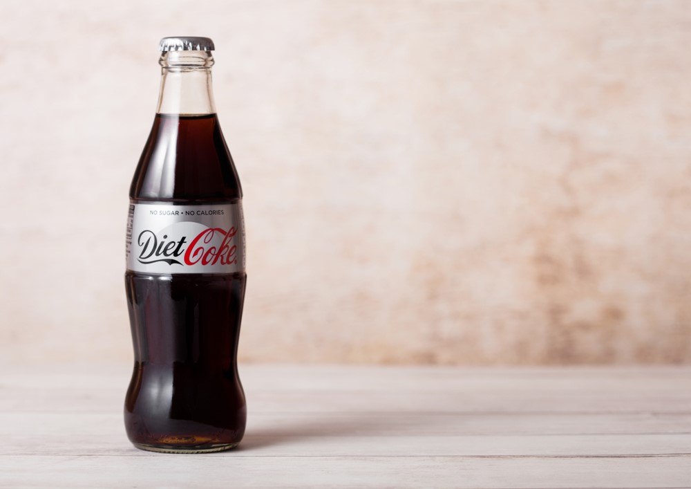 A bottle of diet coke standing on a desk or table