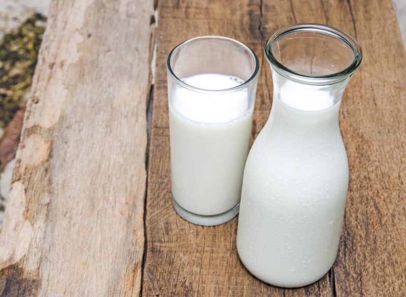 A bottle of milk and a glass of milk on a table