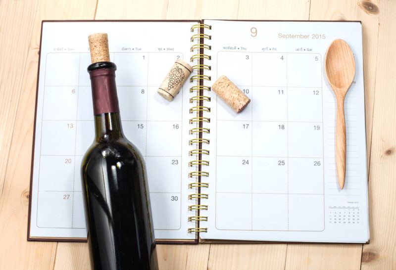 A bottle of red wine, two corks and a spoon on a calendar