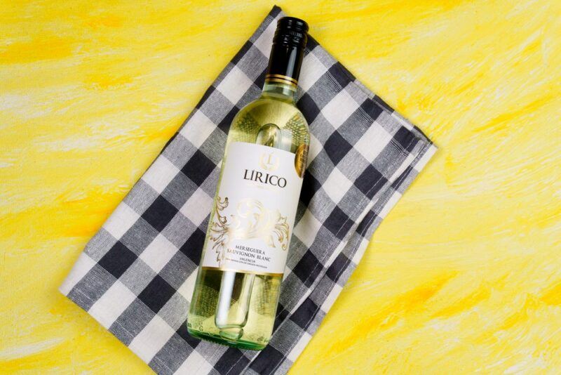 A yellow table with a black and white cloth and a bottle of sauvignon blanc