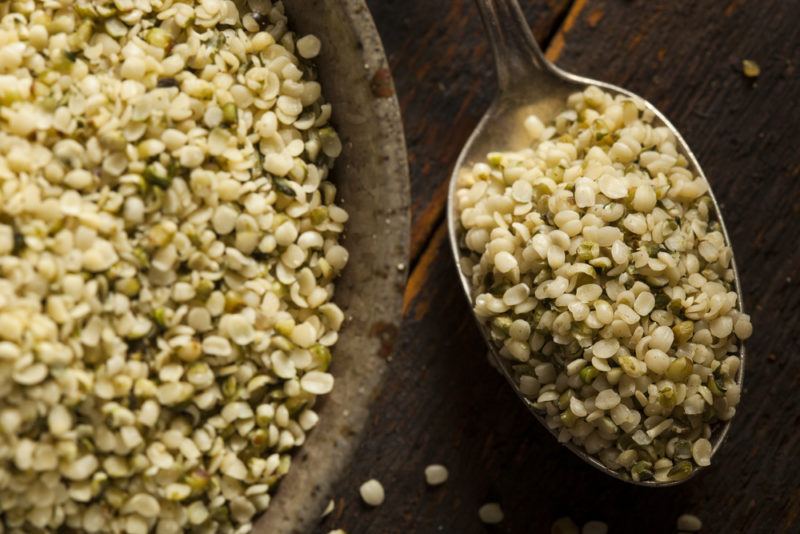 A large brown bowl of hemp hearts next to a spoon