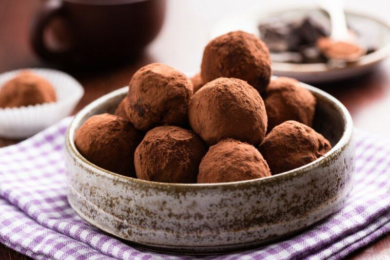 A bowl of keto chocolate truffles on a purple and white cloth