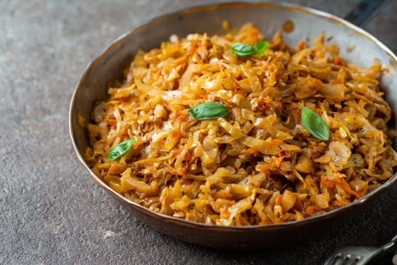 A large bowl containing fried cabbage that's going to be used as noodles