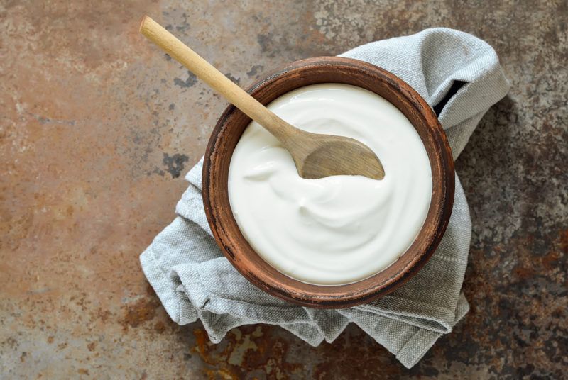 A wooden bowl that contains full fat yogurt