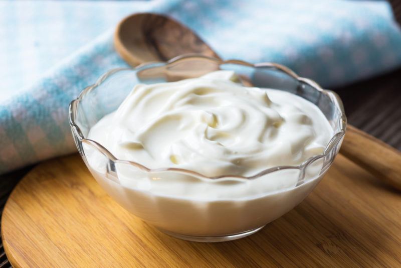 A glass bowl containing Greek yogurt and a spoon