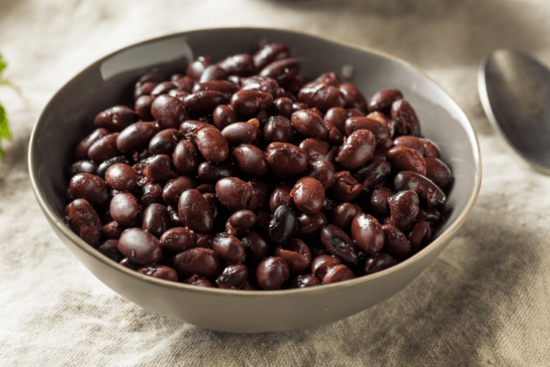 A large bowl containing black beans that have been poured straight from a can