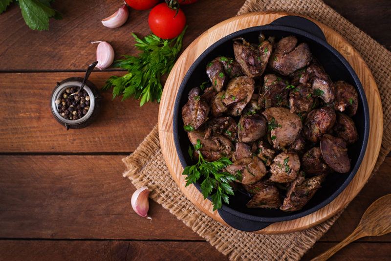 A brown bowl with cooked liver on a wooden table