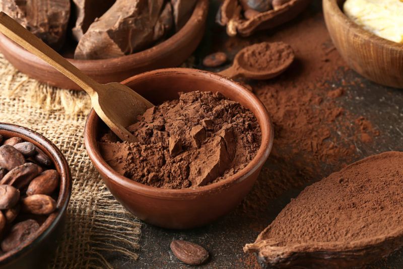 A bowl of cocoa with cacao seeds in bowls on a table