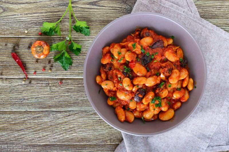 A white bowl with baked beans in sauce