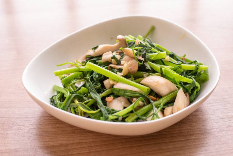 A white bowl with cooked river weed called rua muong