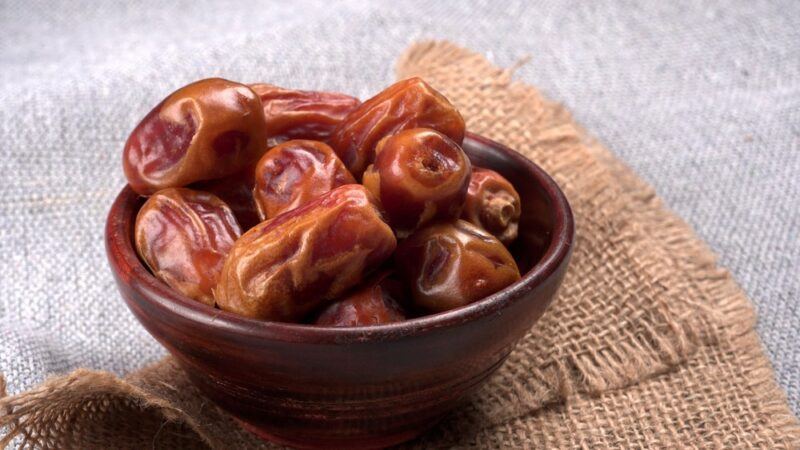 A bowl of dates on a light background and a cloth