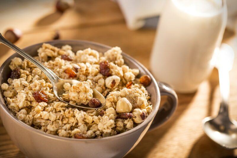 A grown bowl of granola next to a glass of milk