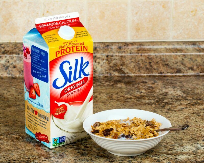 A white bowl filled with cereal next to a carton of Silk almond milk