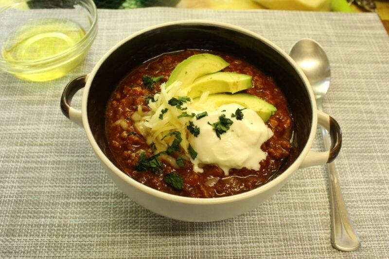 A large bowl containing keto chili that doesn't use beans and is topped with avocado and sour cream