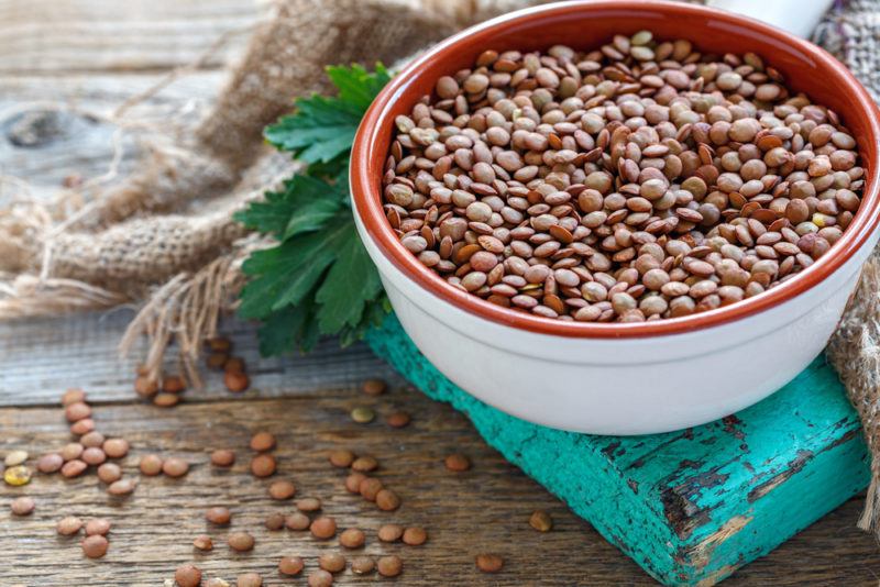 A white and red bowl filled with raw lentils